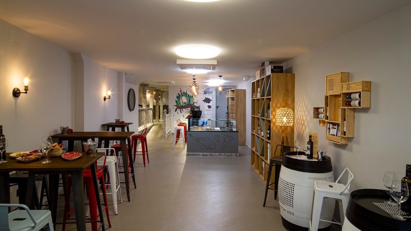 Interior del bar con mesas altas y estanterías de vino